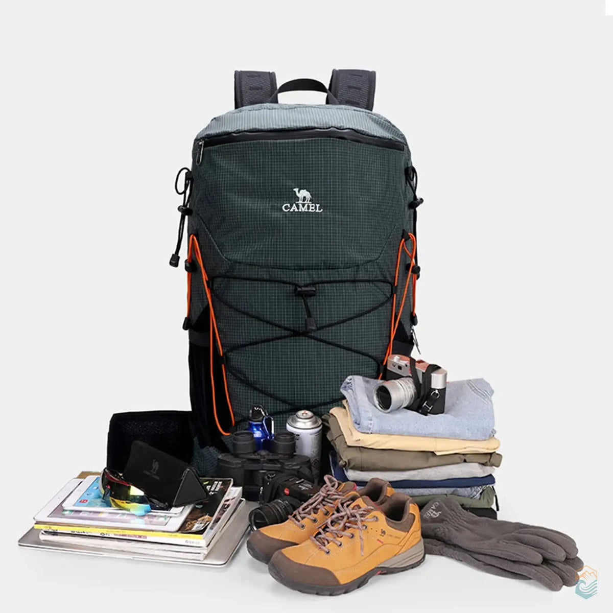 Camel outdoor backpack in dark green, displayed with packed hiking and camping gear including boots, clothing, camera, binoculars, and essentials, ideal for outdoor adventures.