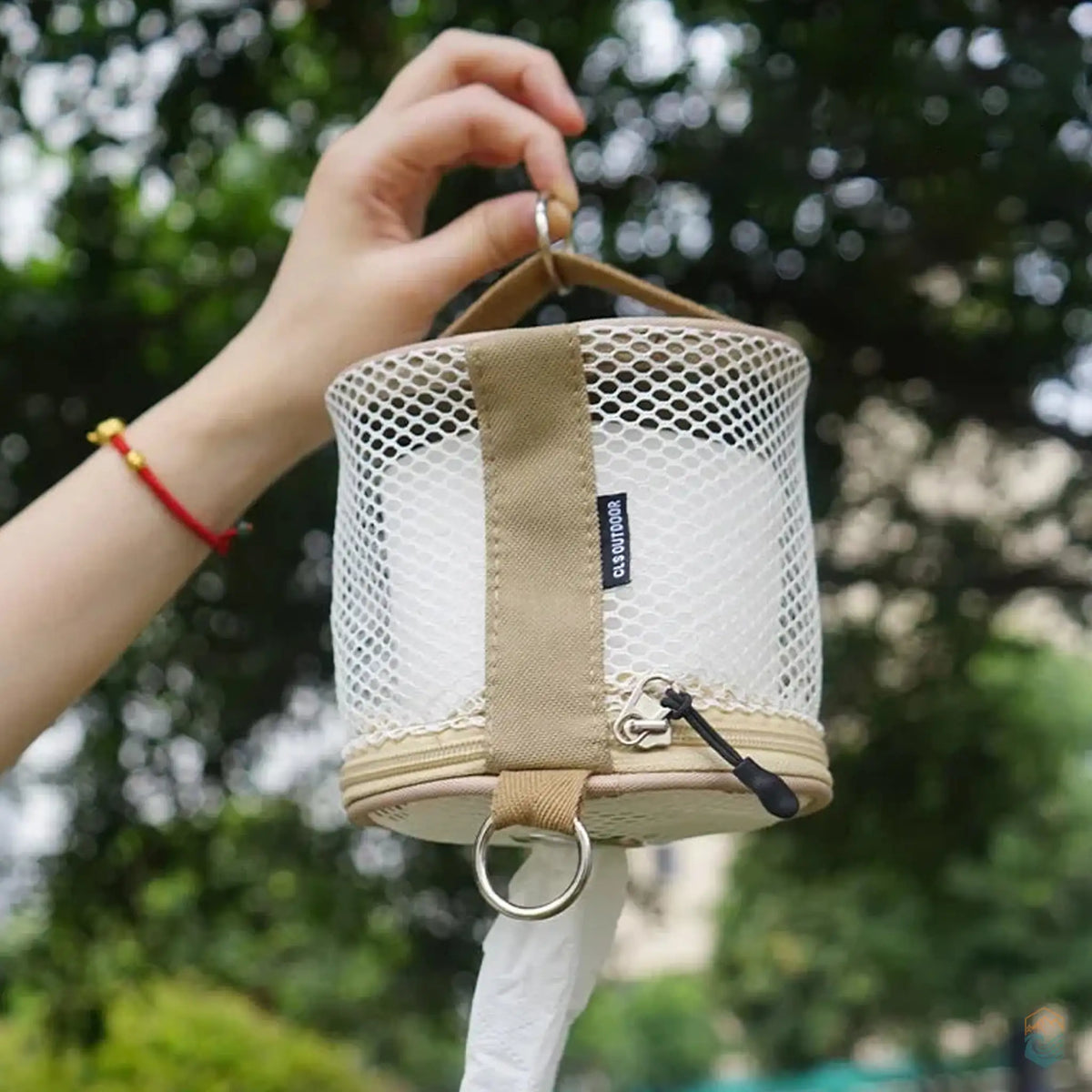 Person holding a CLS outdoor toilet paper storage case, showcasing the hanging loop and mesh design for convenient outdoor use