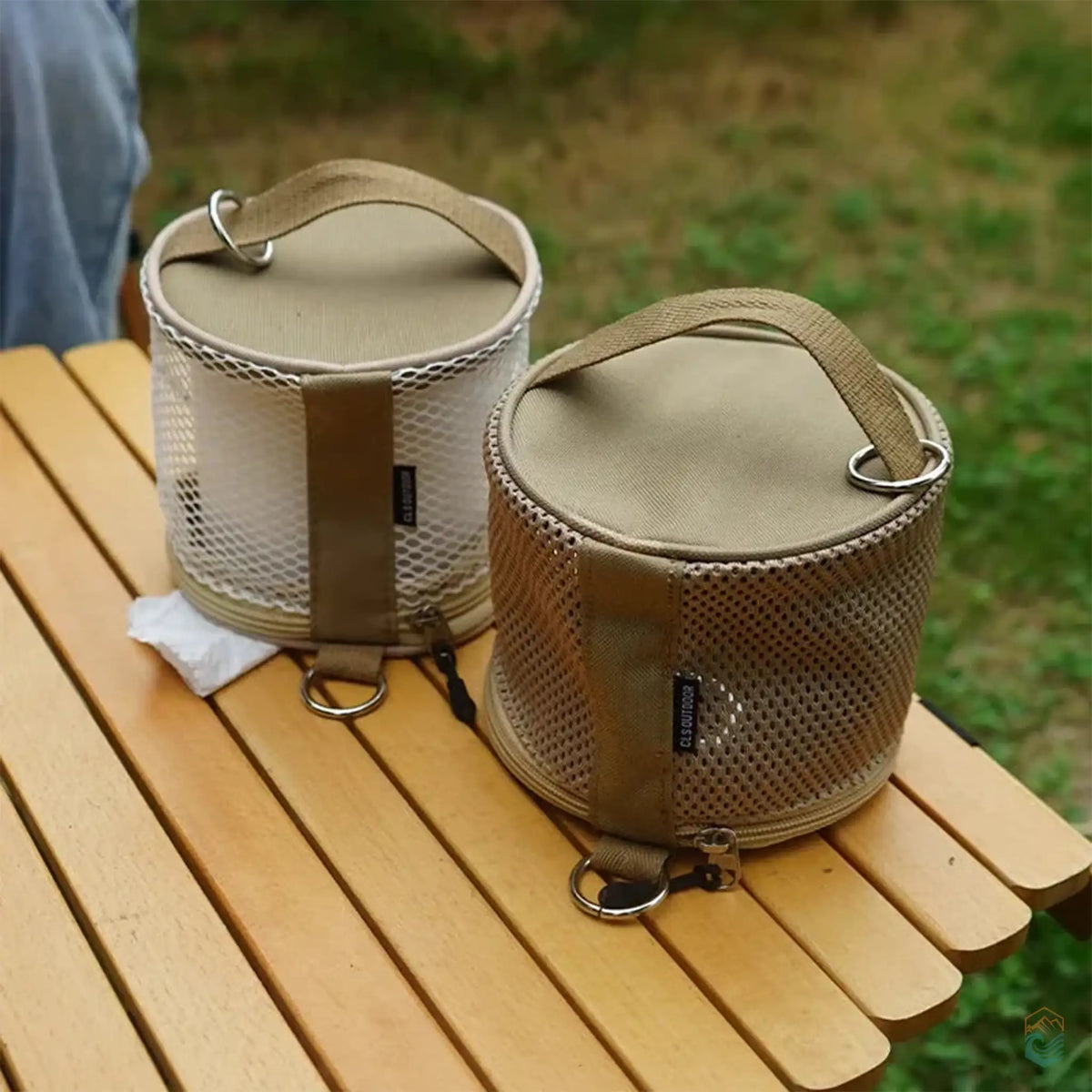 Two CLS outdoor toilet paper storage cases placed on a wooden table, highlighting the mesh design and portability for camping