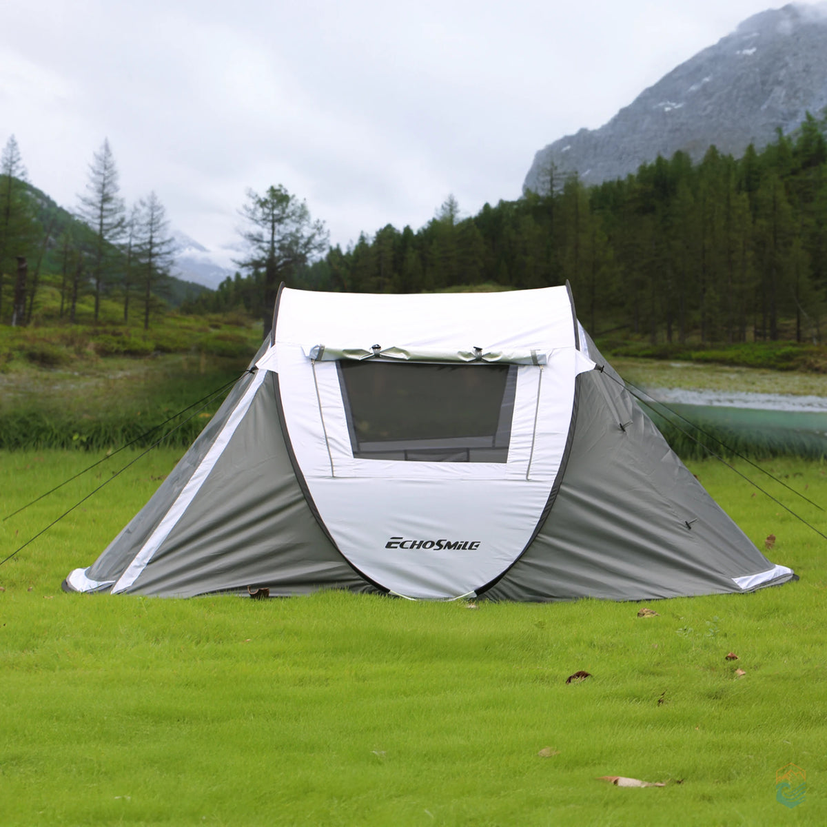 EchoSmile 5-person pop-up camping tent staked on grassy terrain in a mountain valley, showcasing front window and weather protection in a scenic outdoor setting