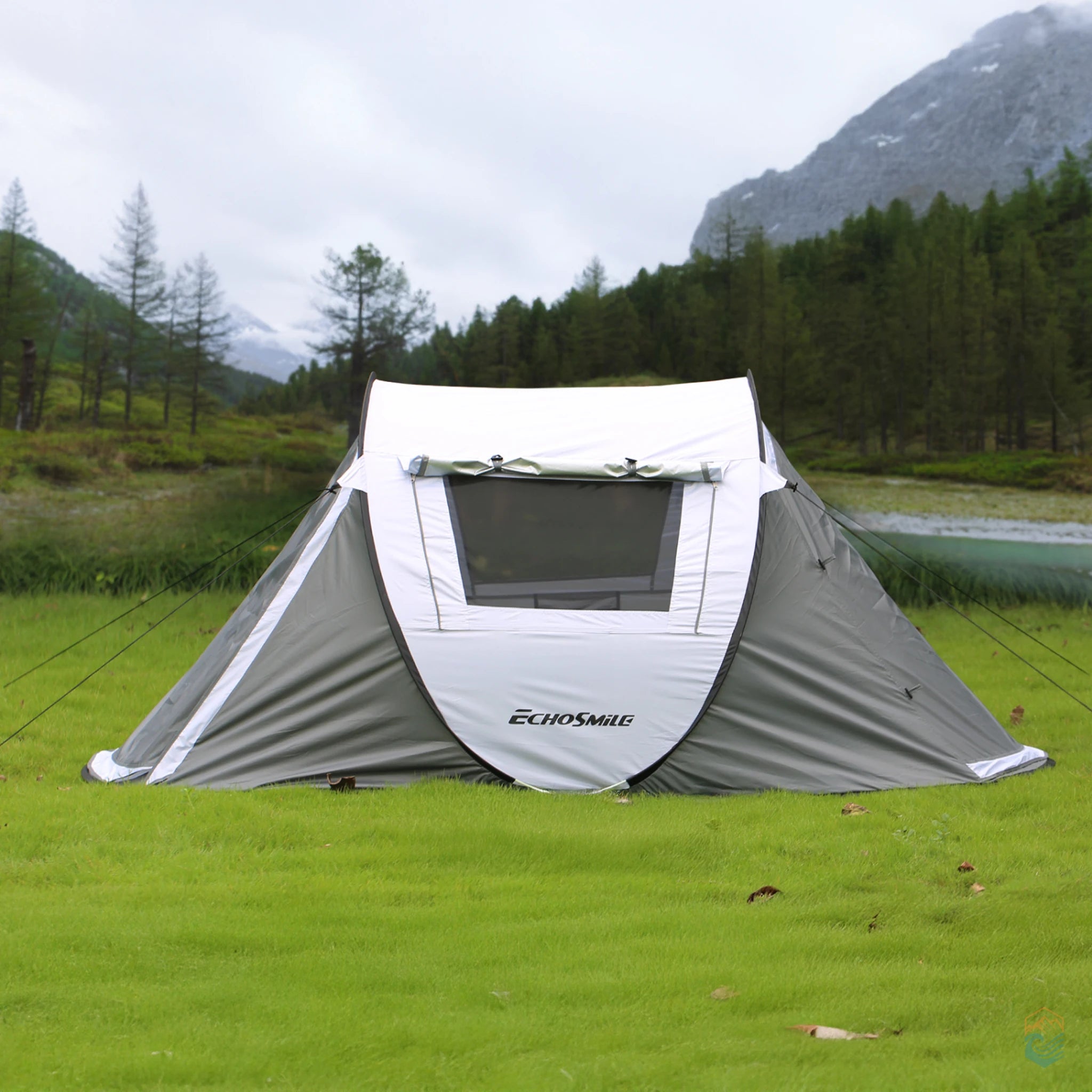 EchoSmile 5-person pop-up camping tent staked on grassy terrain in a mountain valley, showcasing front window and weather protection in a scenic outdoor setting