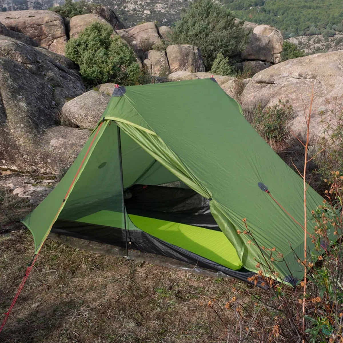 FLAME'S CREED Lanshan 2 Pro green ultralight tent set up in a rocky wilderness with front door open, showing mesh interior and sleeping pad—perfect for solo or duo backpacking in rugged terrain with clear weather conditions