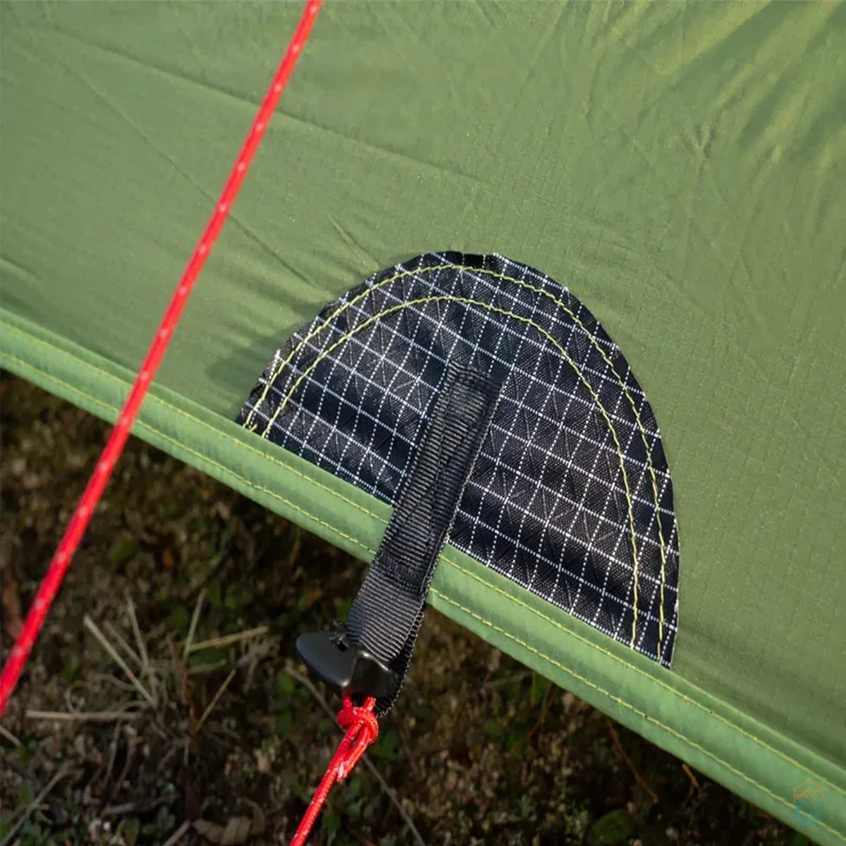 Close-up of the reinforced anchor point with black grid-patterned fabric and red guyline on the green FLAME'S CREED Lanshan 2 Pro tent, designed for enhanced wind stability on rugged terrain.