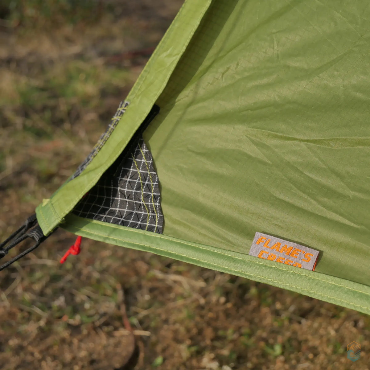 Detail of FLAME'S CREED Lanshan 2 Pro green tent showing reinforced corner stitching with grid-patterned fabric and brand label, designed for added durability during backcountry.