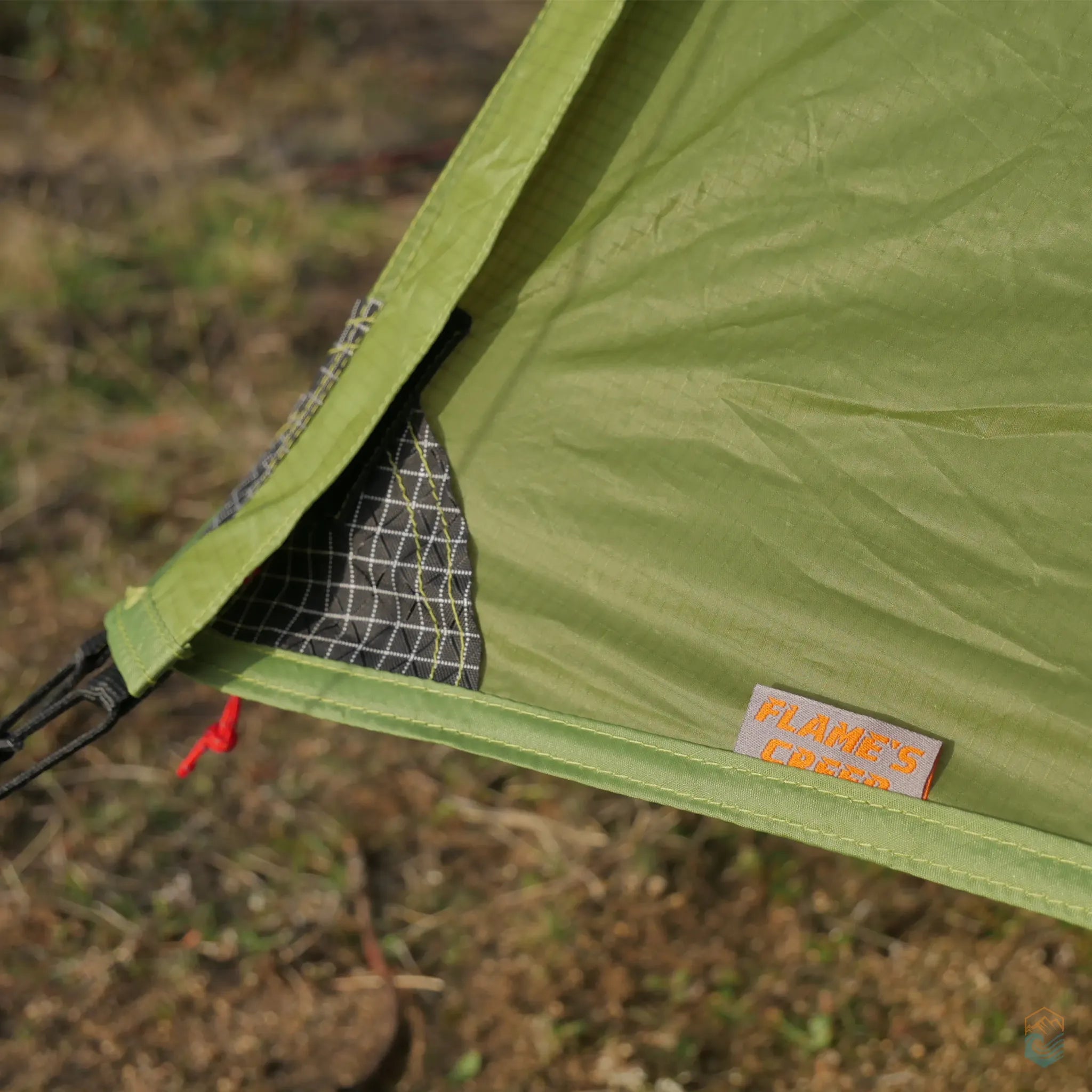Detail of FLAME'S CREED Lanshan 2 Pro green tent showing reinforced corner stitching with grid-patterned fabric and brand label, designed for added durability during backcountry.