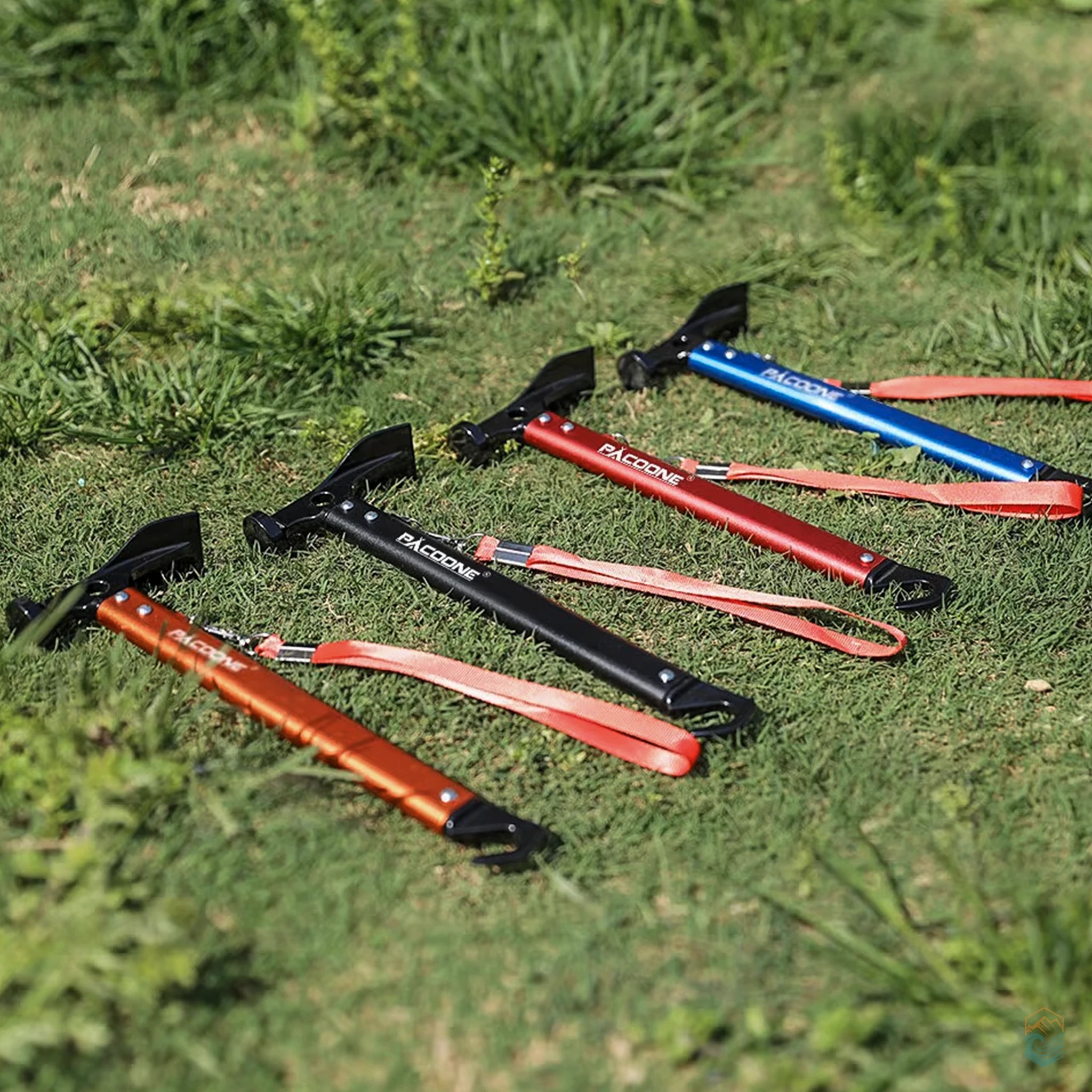 Pacoone camping hammer multi-tools in orange, black, red, and blue arranged on grassy field, showcasing durable construction, ergonomic shape, and color options for outdoor use