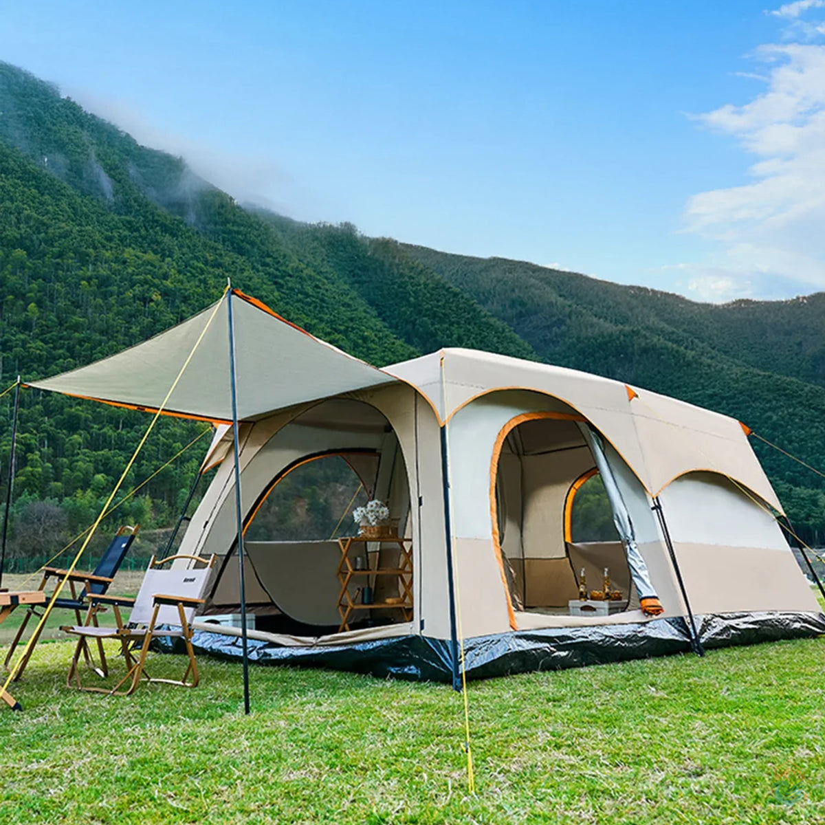 Sonuto khaki family camping tent set up on grass with canopy extended, surrounded by chairs and gear, mountain view in background
