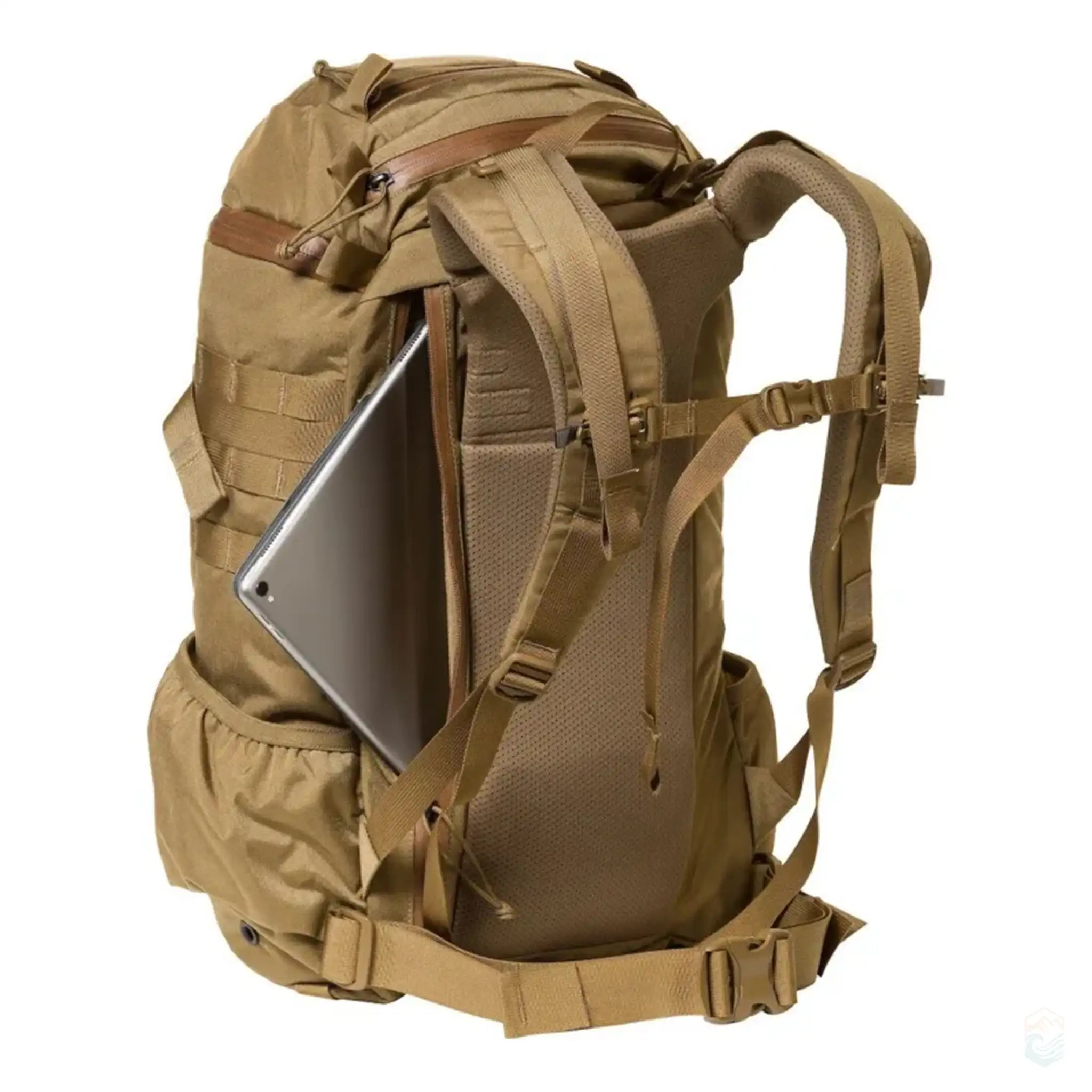Tan Mystery Ranch hiking backpack with a padded laptop compartment, adjustable shoulder straps, and back padding for support. The side view highlights the secure fit for electronic devices and the MOLLE strap system.