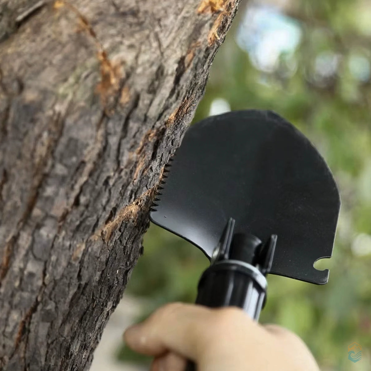 Black folding camping shovel in action, sawing into a tree trunk with its serrated edge, demonstrating multi-tool functionality for outdoor survival and emergency tasks