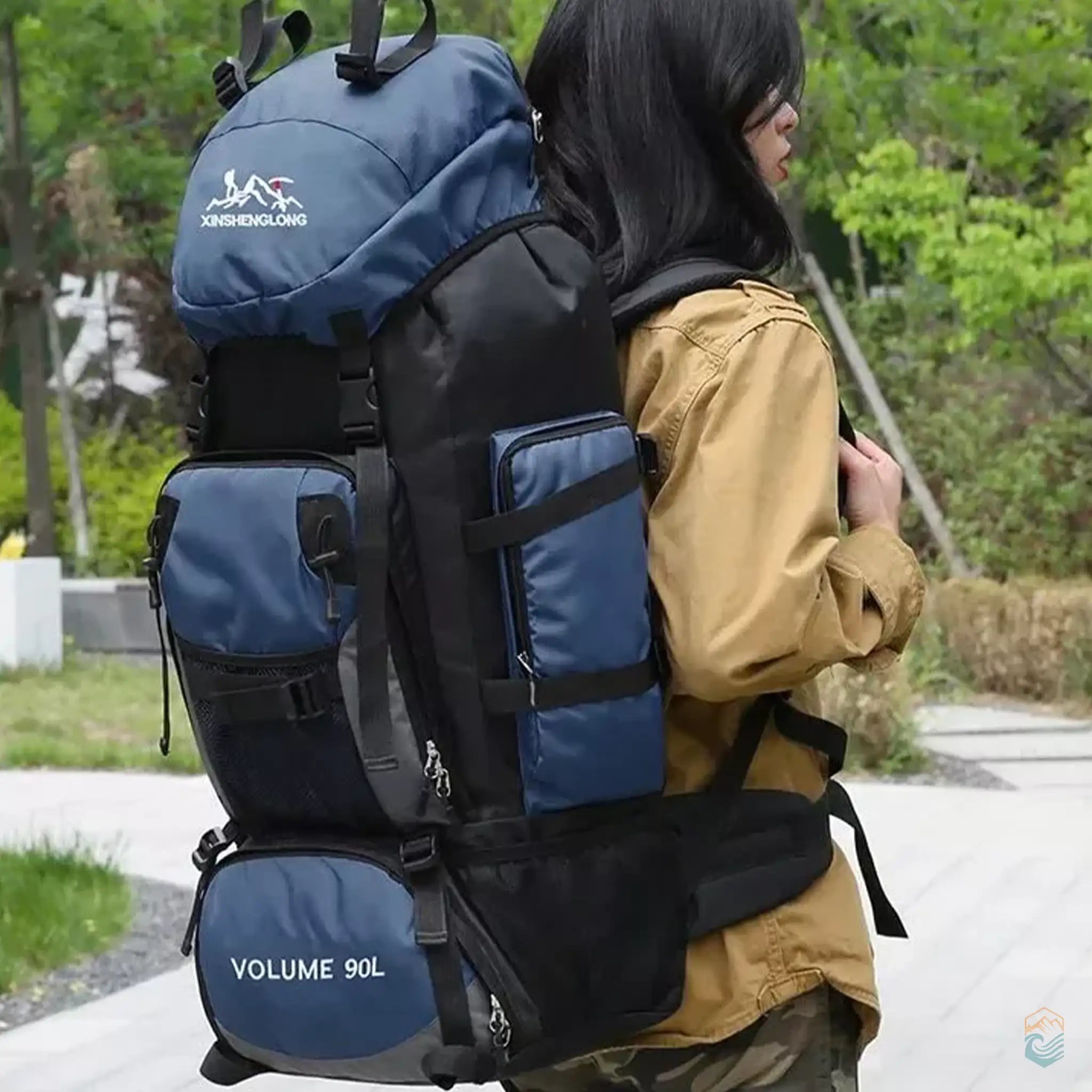 A person wearing a deep blue 90L hiking backpack outdoors, showcasing the backpack's large capacity, secure strap system, and multiple compartments, ideal for extended hiking and camping trips.