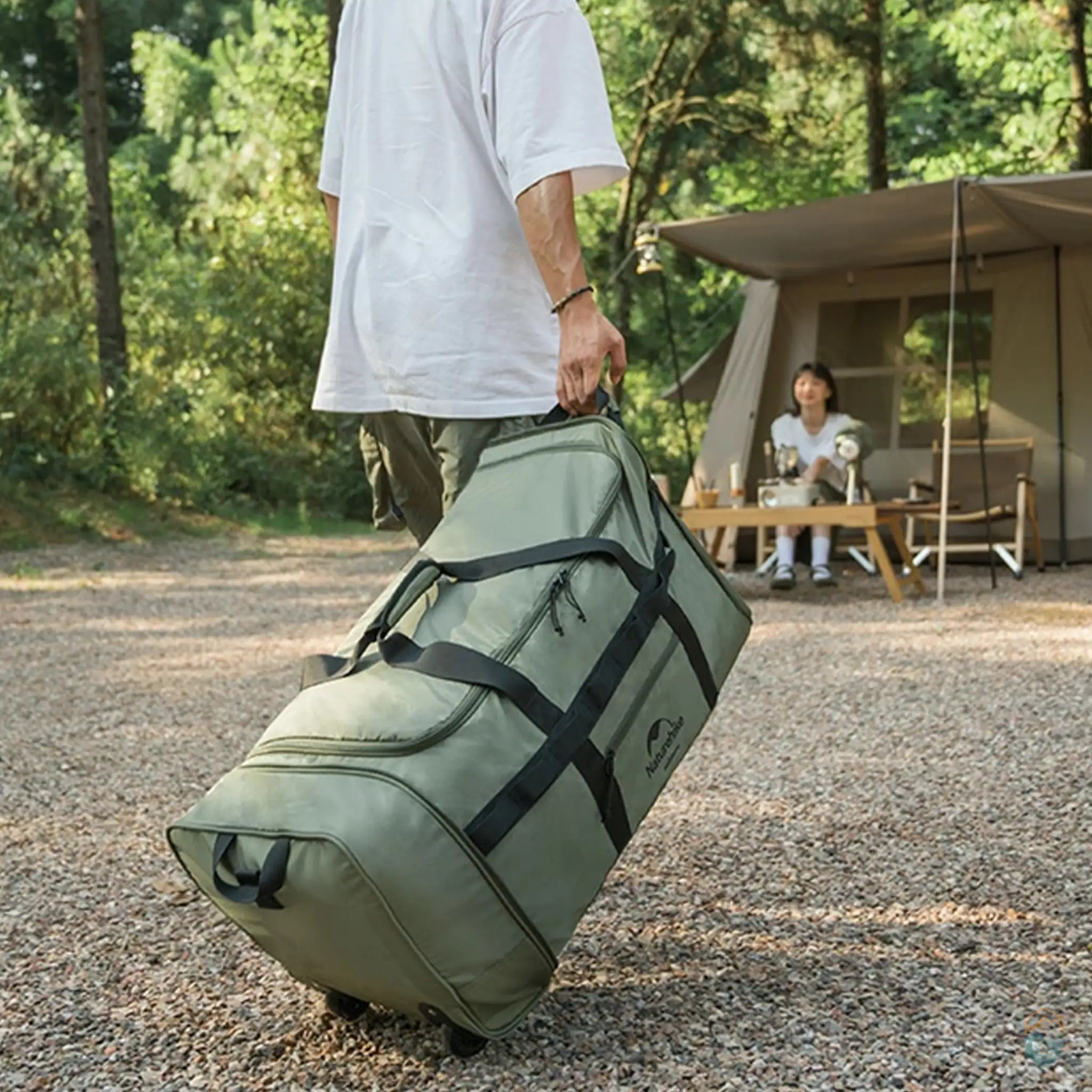 Lifestyle image of a person transporting the green Naturehike foldable camping storage bag with wheels at a campsite. The bag's large 88L capacity and convenient rolling design make it ideal for carrying camping gear in outdoor settings.