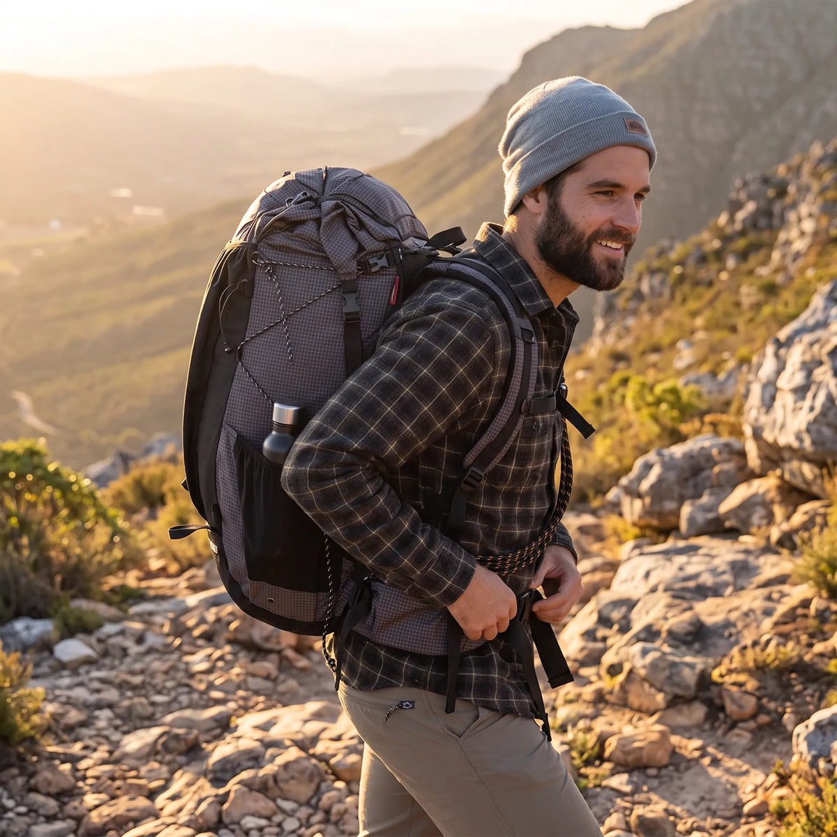 Hiker wearing the Naturehike 60L+5L ultralight hiking backpack while walking along a rocky mountain trail during golden hour.