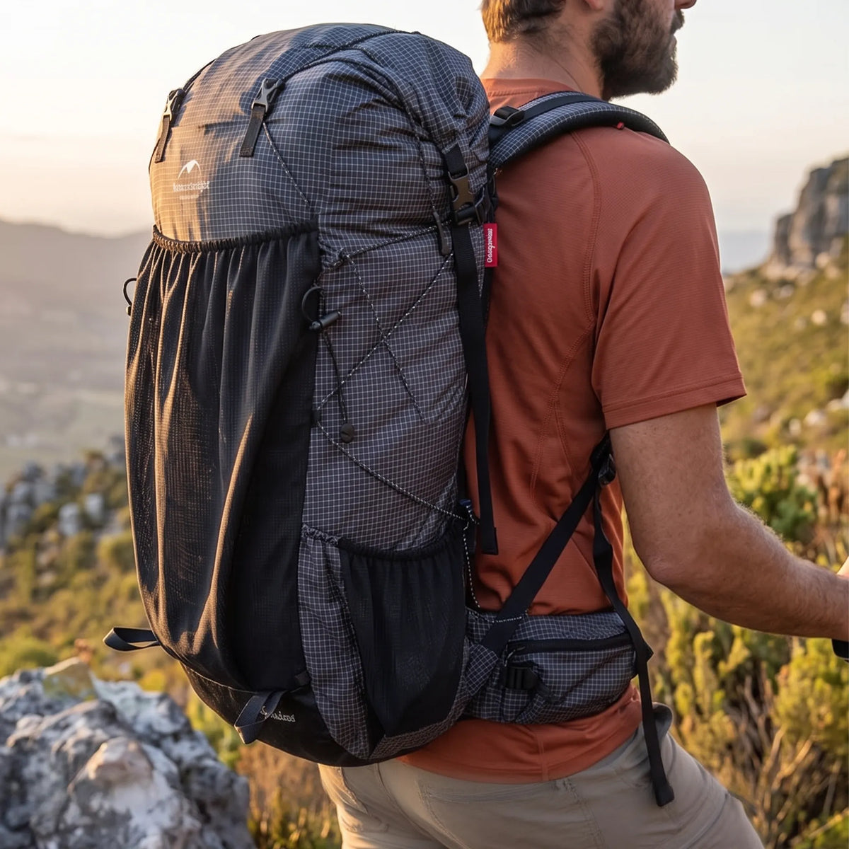 Hiker wearing the Naturehike 60L+5L ultralight hiking backpack while trekking across a mountain trail during golden hour.