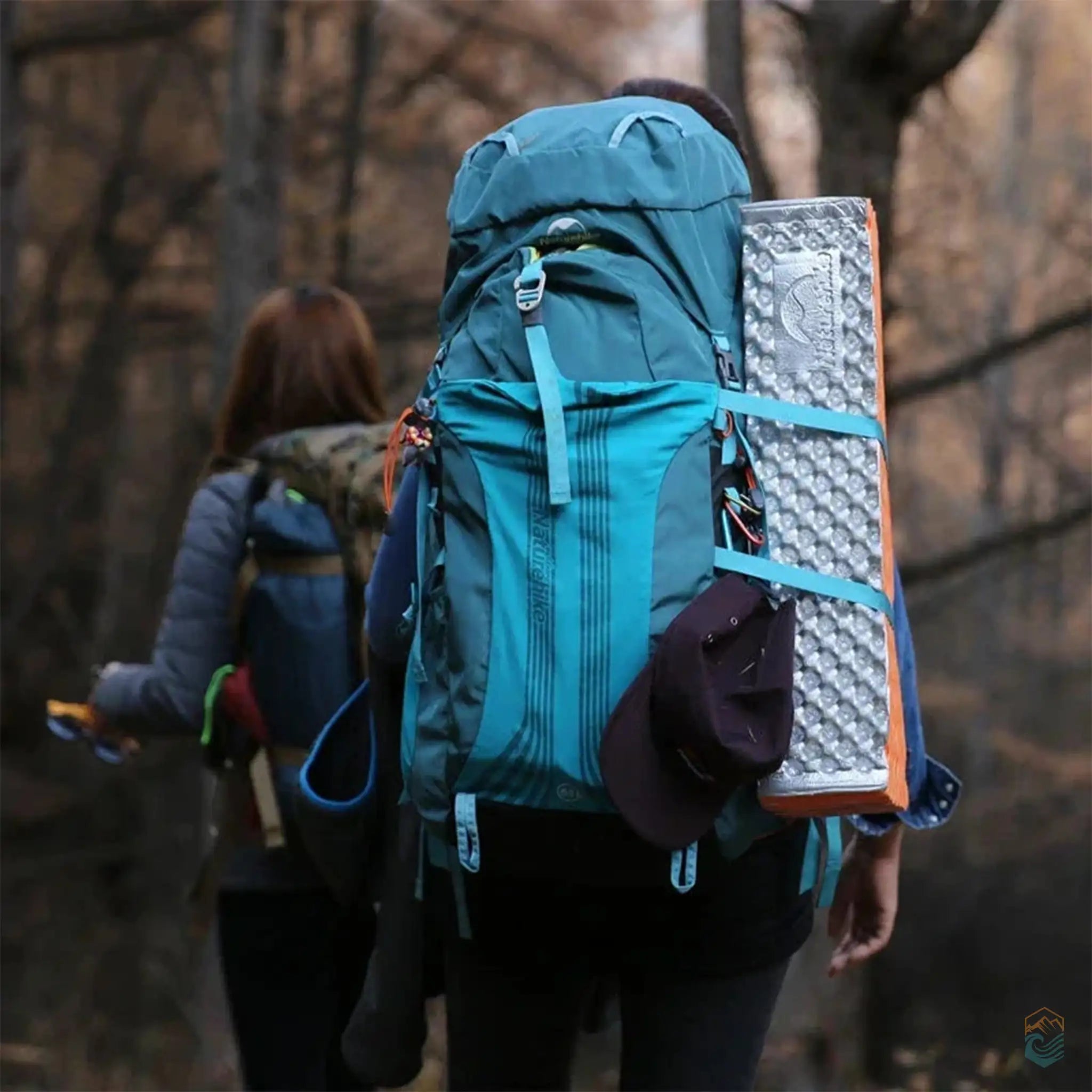 A hiker with a Naturehike backpack carrying a camping mat, walking through a dense forest, showcasing the backpack's durability and ample storage for outdoor adventures.