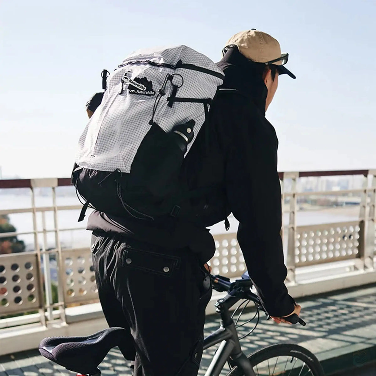 Person wearing a Naturehike white grid outdoor hiking backpack while cycling, showcasing the backpack’s versatile design, perfect for both urban commuting and outdoor adventures.