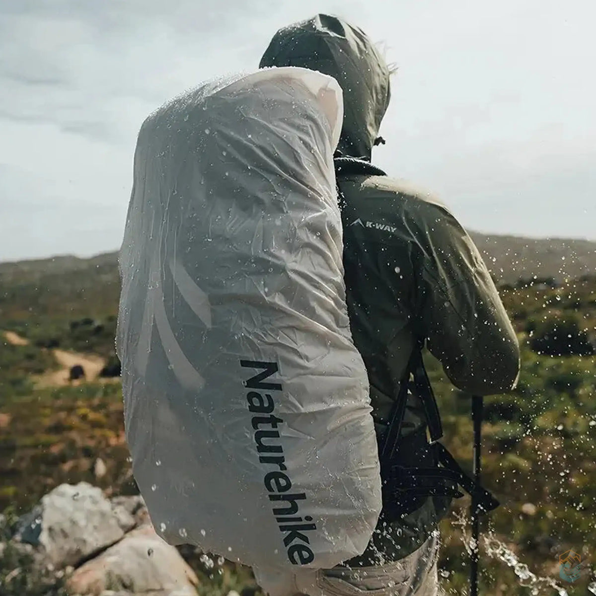 Hiker wearing a Naturehike backpack with rain cover during a rainy hike, showcasing the waterproof protection in an outdoor setting.