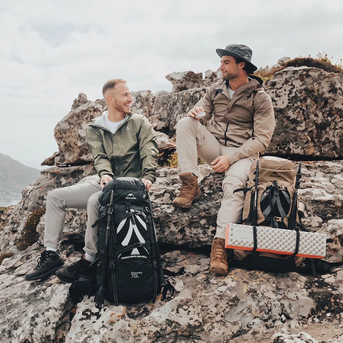 Two hikers relaxing at a mountain campsite with Naturehike Discovery 70L backpacks after a day of backpacking and hiking.