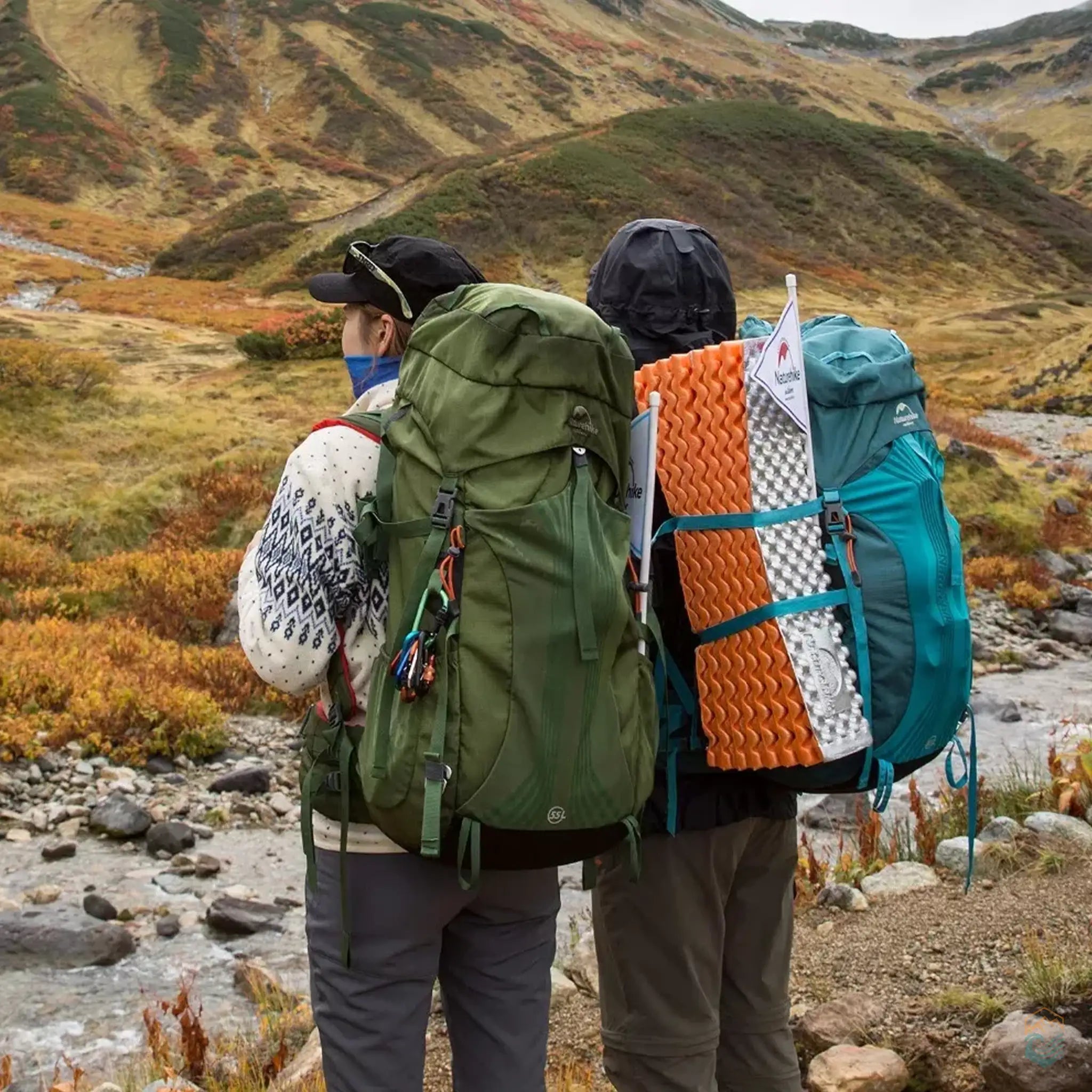 Two hikers equipped with Naturehike backpacks trekking through a mountainous landscape, showcasing the durability and storage capacity of the backpacks in a natural outdoor setting.