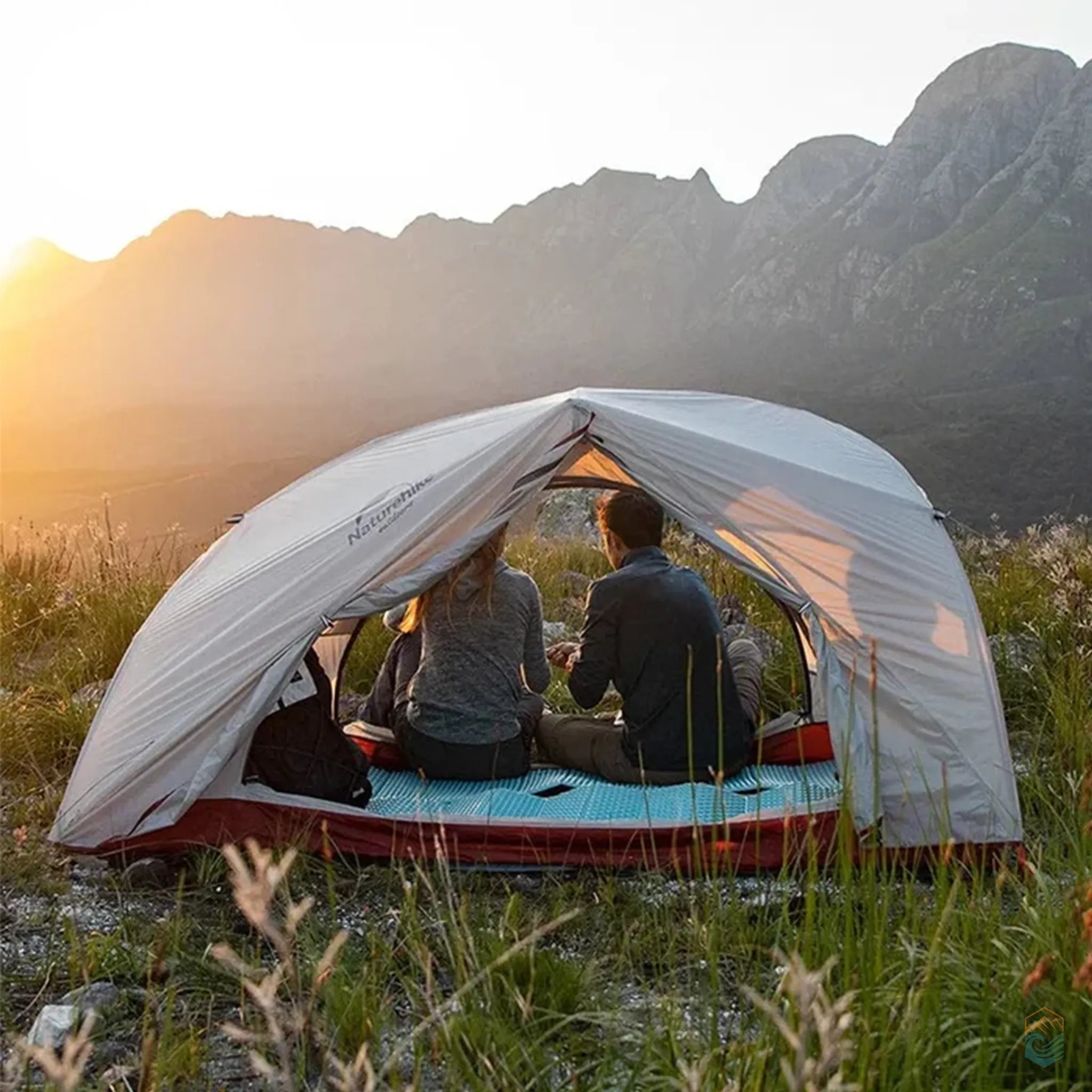 Two campers sitting inside the Naturehike Star River 2-person tent at sunset with mountain views in the background, showcasing the tent in a real outdoor setting