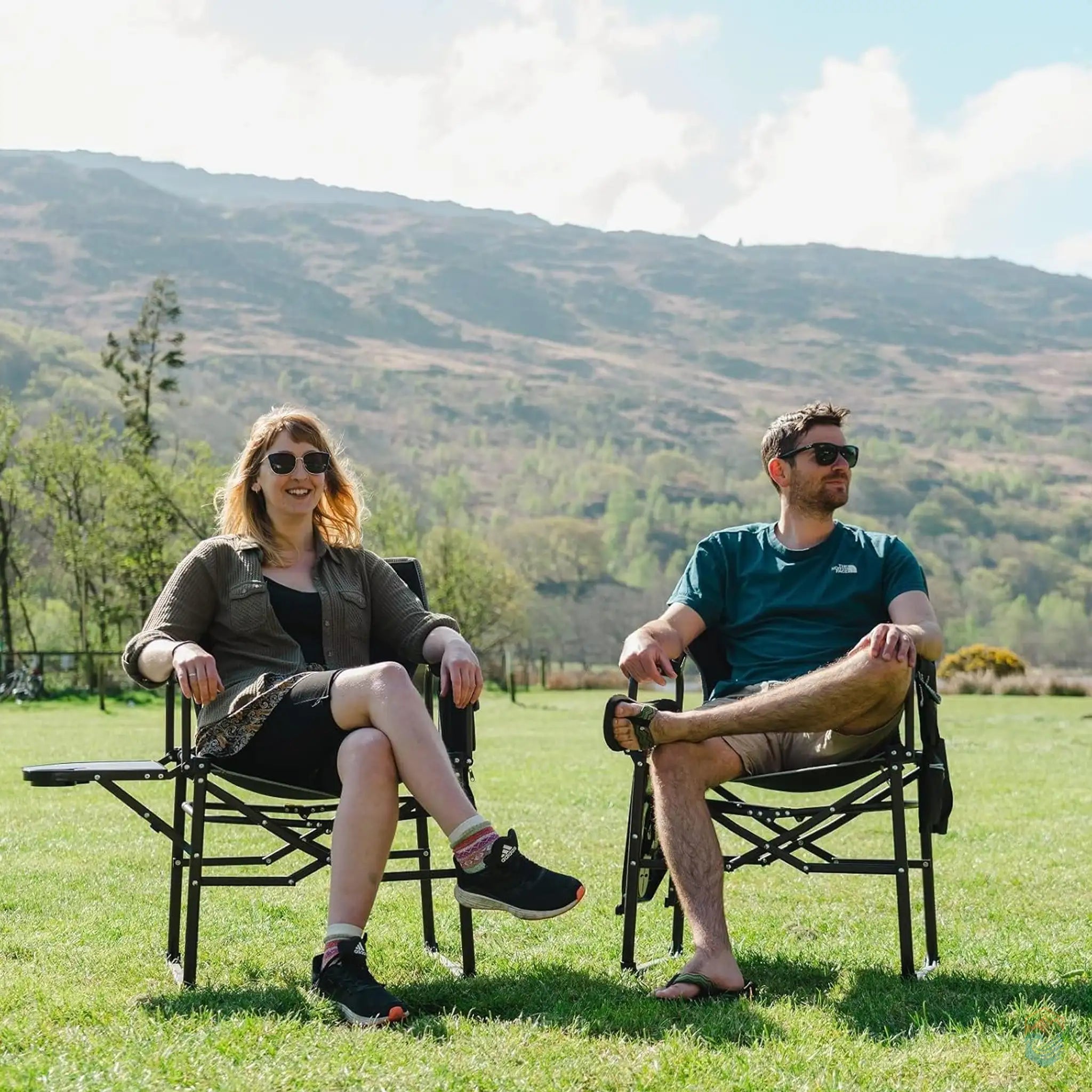 Two people sitting comfortably in SunnyFeel heavy-duty folding camping director's chairs with side tables in a sunny outdoor landscape