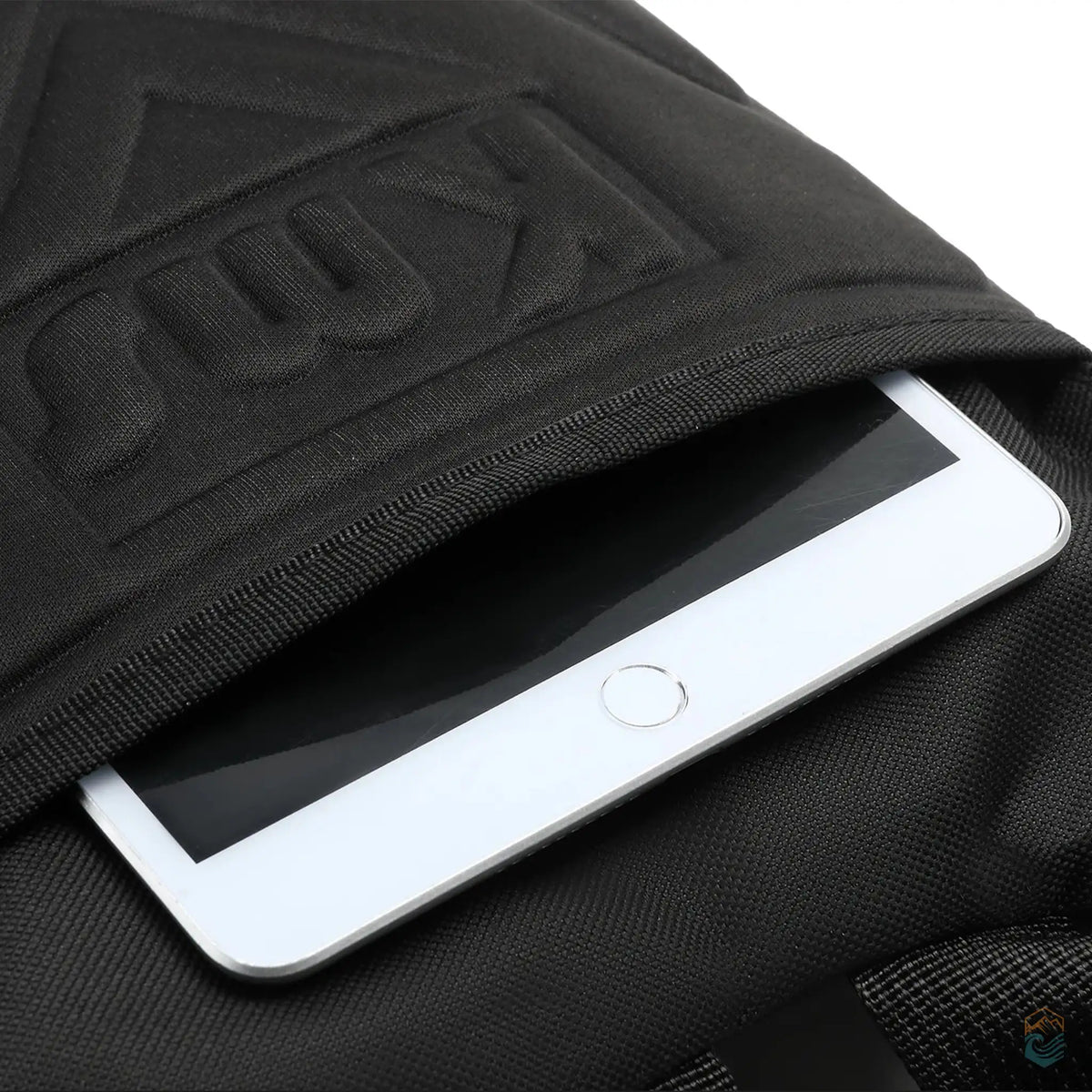 Close-up of deep back pocket on black tactical hydration pack, showing an iPad securely stored inside.