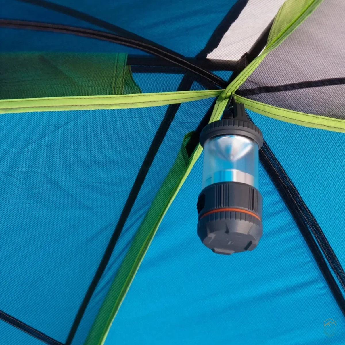 Close-up of a camping lantern hanging from a hook at the center of a blue and green dome tent interior
